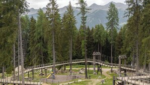 Metsäinen alue, jossa on puinen silta, leikkikenttä ja piknikpöytiä.