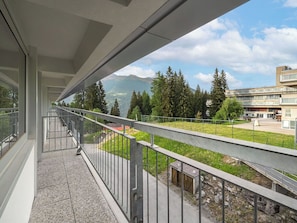 A balcony with a metal railing overlooking a grassy area with trees and a building in the background. - Beautiful apartment for 4 people with WIFI, TV and balcony (Mezzana)