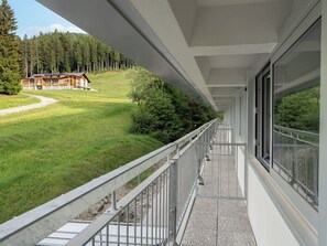 Ein Balkon mit Blick auf eine bewaldete Landschaft und ein Gebäude.