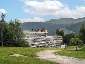 Monikerroksinen hotelli, jossa on tasakatto, ravintola alakerrassa ja näkymä vuorille kauempana.