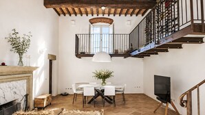 Un'ampia zona giorno con camino, un tavolo da pranzo con sedie, una televisione e una scala che conduce a un balcone.