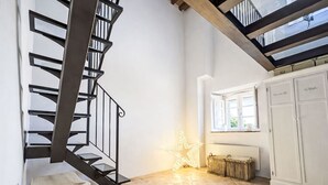 Una scala con ringhiera in metallo, una panca in legno, una decorazione luminosa a forma di stella e una finestra che si affaccia sul verde.