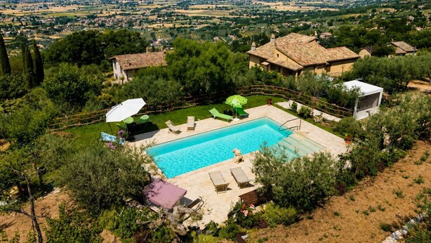 Ein Pool mit Blick auf eine ländliche Landschaft, umgeben von Bäumen und Gebäuden.