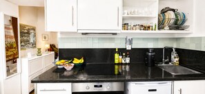 Eine Küche mit schwarzem Arbeitsplatz, Edelstahlgeräten und einer gefliesten Spritzschutzwand.
