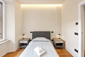 A bedroom with a bed, two bedside tables, a window, and a door. - Modern Central Penthouse with Private Panoramic Terrace (Siena)