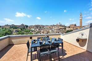 A terrace with a table set for breakfast, overlooking a historic cityscape with a prominent tower. - Modern Central Penthouse with Private Panoramic Terrace (Siena)