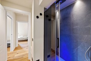 Ein Flur mit einem Bett, einem Duschbereich mit blauer Beleuchtung und einem Holzboden.