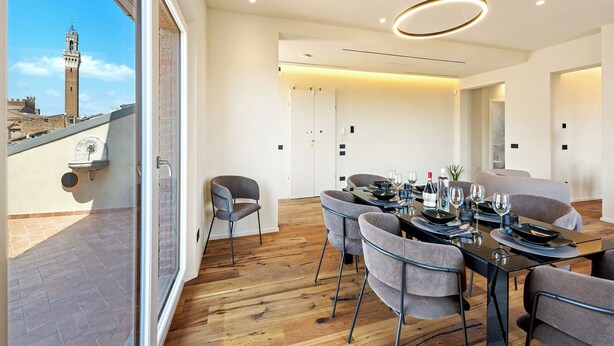 Een moderne eetruimte met een houten vloer, grijze gestoffeerde stoelen en een tafel voor vier personen.