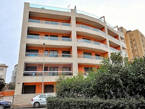 A multi-story building with balconies, a car parked in front, and a hedge in the foreground. - Family Apartment in Lloret de Mar, 300m Beach, Air Conditioning, Parking (Lloret de Mar)