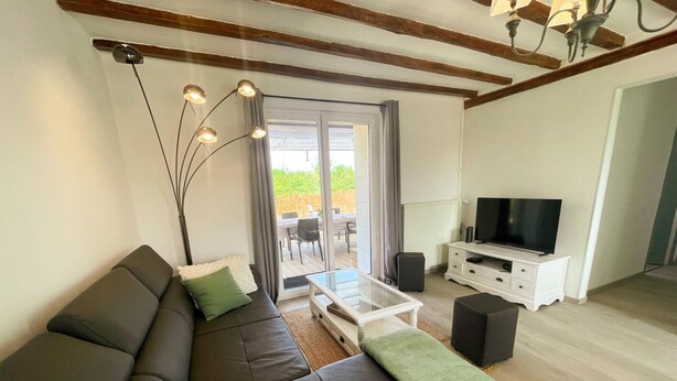 A modern living room with a sofa, TV, and a glass coffee table. - Charming house near castles - 4 guests (Orbigny)