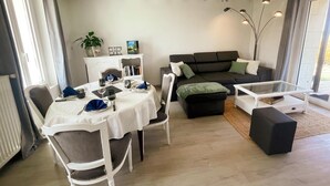 A dining area with a table set for four, a sofa, and a coffee table. - Charming house near castles - 4 guests (Orbigny)
