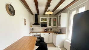 A compact kitchen with a wooden table, black chairs, white cabinets, and a black refrigerator. - Charming house near castles - 4 guests (Orbigny)