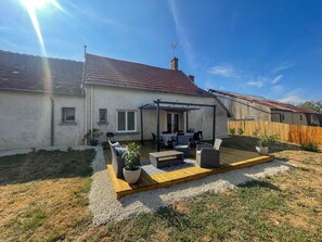Ein Haus mit Terrasse, Gartenmöbeln und einem umzäunten Hof.