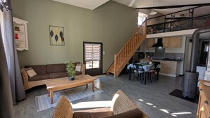 Una sala de estar con sofá, una mesa de centro y una escalera que lleva a una zona de cocina.