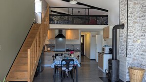 Una cocina moderna con comedor, escalera de madera y un espacio tipo loft.
