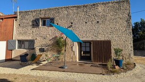 Un edificio de piedra con una puerta de madera, una ventana pequeña y un paraguas azul.