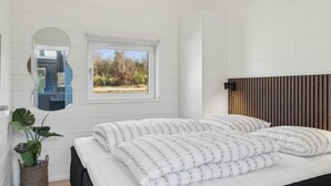 Een slaapkamer met een bed, een raam, een spiegel en een plant.