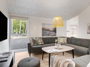 Ein modernes Wohnzimmer mit einem grauen Sofa, einem Couchtisch und einem großen Fenster.