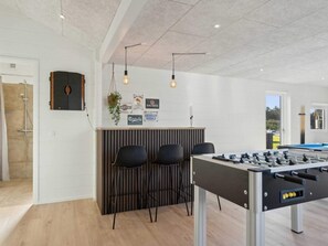 Ein Zimmer mit Kicker, einer Bar mit Sitzgelegenheiten und einer Dusche.