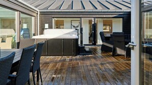 Een terras met buitenmeubilair, een hottub en een schuifdeur naar een kamer.