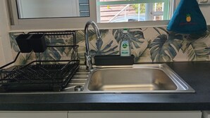 Cuina amb un rentaplatets d'acer inoxidable, un escorredor i una ampolla de sabó líquid.