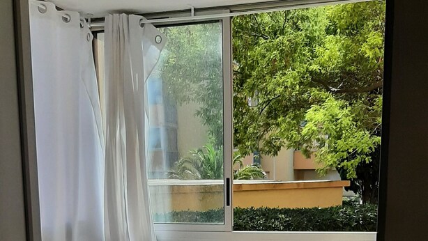 Un dormitorio con cama, una mesita de vidrio y un balcón con sillas.