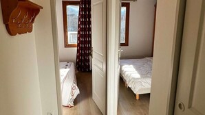 Een kamer met twee bedden, een houten plank en een raam met gordijnen.