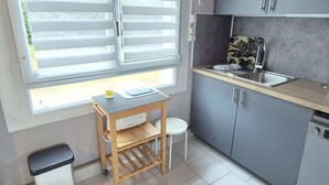 Cocina compacta con ventana, una mesita y armarios grises.