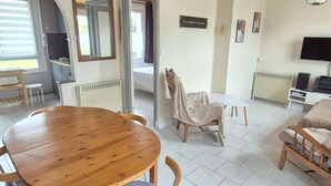 Una sala acogedora con una mesa de comedor de madera, un sofá y un televisor.