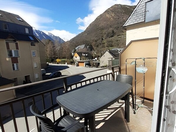 Un balcon avec une table et des chaises, donnant sur un paysage montagneux parsemé de bâtiments.
