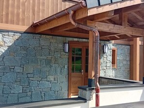 Fachada de pedra amb una porta de fusta i una canonada de metall.