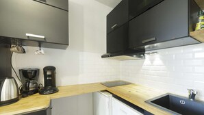 Uma cozinha compacta com cafeteira, chaleira e máquina de lavar louça.
