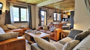 A cozy living room with leather sofas, a wooden coffee table, and a kitchen in the background.