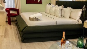 Ein modernes Schlafzimmer mit einem Bett, einem roten Sessel, einem Glastisch mit einer Flasche und einem Bild an der Wand.
