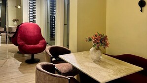 Ein modernes Interieur mit Esstisch, Stühlen, einem roten Sessel, einer Blumenvase und einer Wandleuchte.