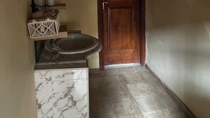 Ein Badezimmer mit Marmorwaschbecken, Holztür und Fliesenboden.