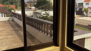 Ein Fenster mit Blick auf ein Gebäude mit rotem Dach und einem Balkon mit Balustraden.