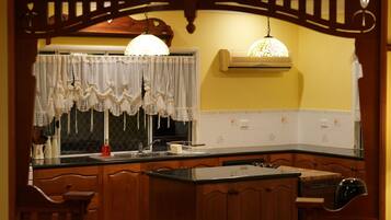 A kitchen with wooden cabinets, a black countertop, a sink, and a hanging light fixture.
