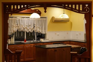 A kitchen with wooden cabinets, a black countertop, a sink, and a hanging light fixture.