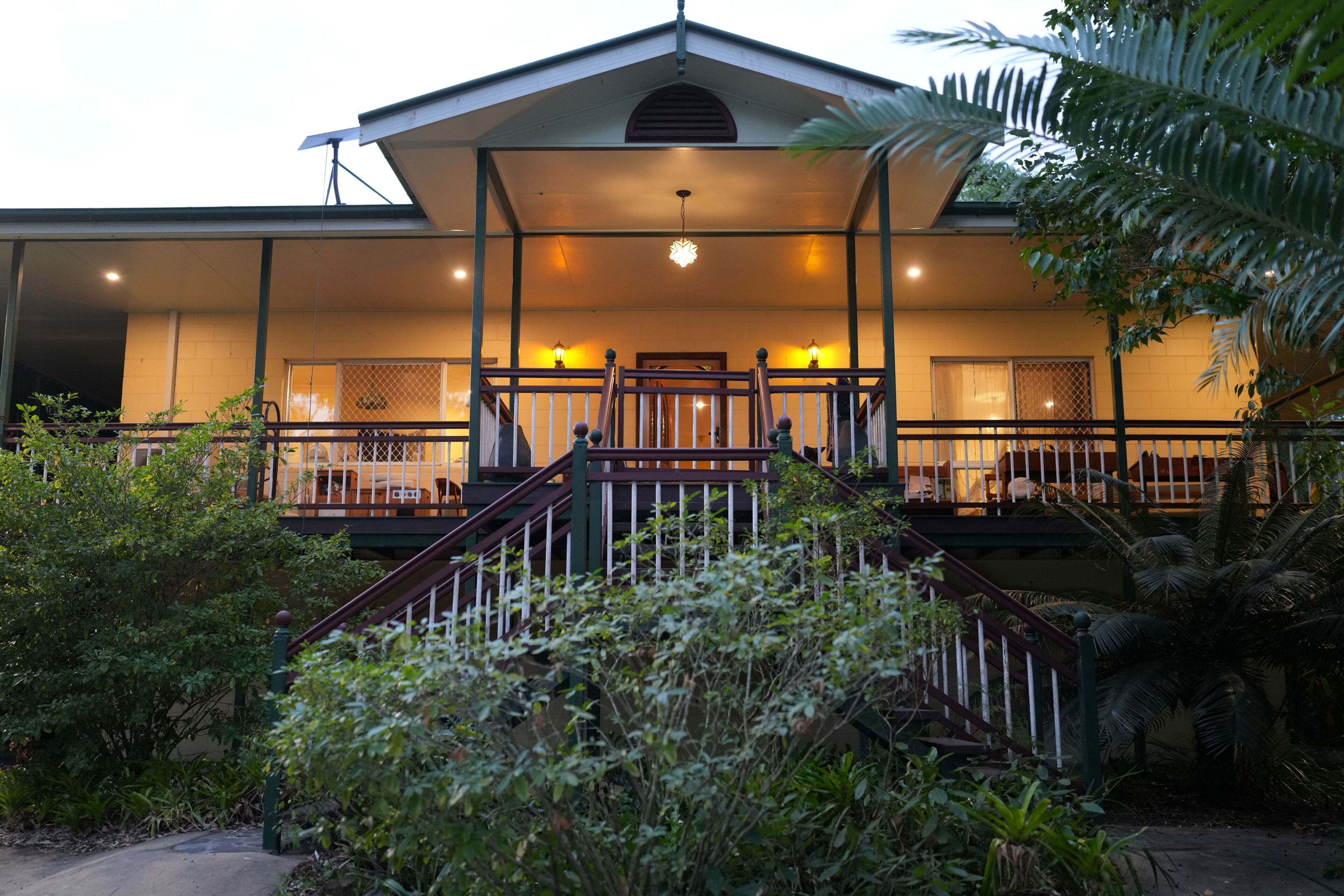A two-story building with a covered entrance, a staircase, and a small outdoor area with plants.