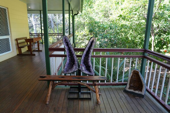 A wooden deck with a bench and two large purple crystals on stands.
