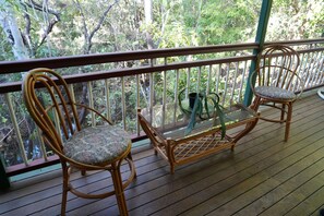 A wooden deck with two wicker chairs and a glass table, overlooking a forested area. - Private Rainforest Retreat | Opposite Billabong Sanctuary (Nome)