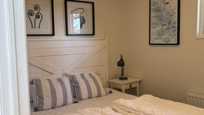 A bedroom with a bed, a nightstand, a lamp, and two framed pictures on the wall. - 4 Star Holiday Home in Uddevalla (Uddevalla)