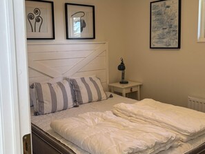 A bedroom with a bed, a nightstand, a lamp, and two framed pictures on the wall. - 4 Star Holiday Home in Uddevalla (Uddevalla)