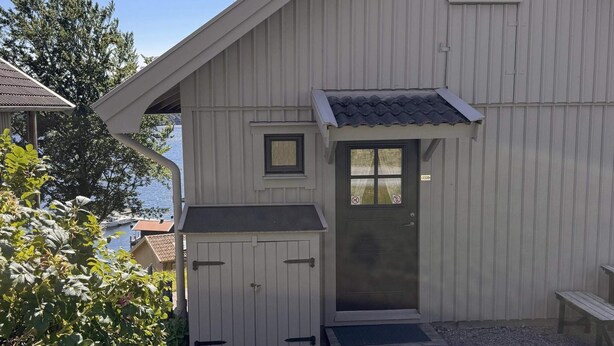 A building with a sloped roof, a door with a window, and a small porch area. - 4 Star Holiday Home in Uddevalla (Uddevalla)
