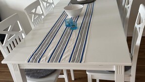 A white dining table with a striped placemat, a white pitcher, a blue glass, and white chairs. - 4 Star Holiday Home in Uddevalla (Uddevalla)