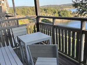 A wooden deck with a table and chairs, overlooking a lake and forested hills. - 4 Star Holiday Home in Uddevalla (Uddevalla)