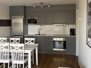A compact kitchen with grey cabinets, a built-in oven, a microwave, and a coffee maker. - 4 Star Holiday Home in Uddevalla (Uddevalla)
