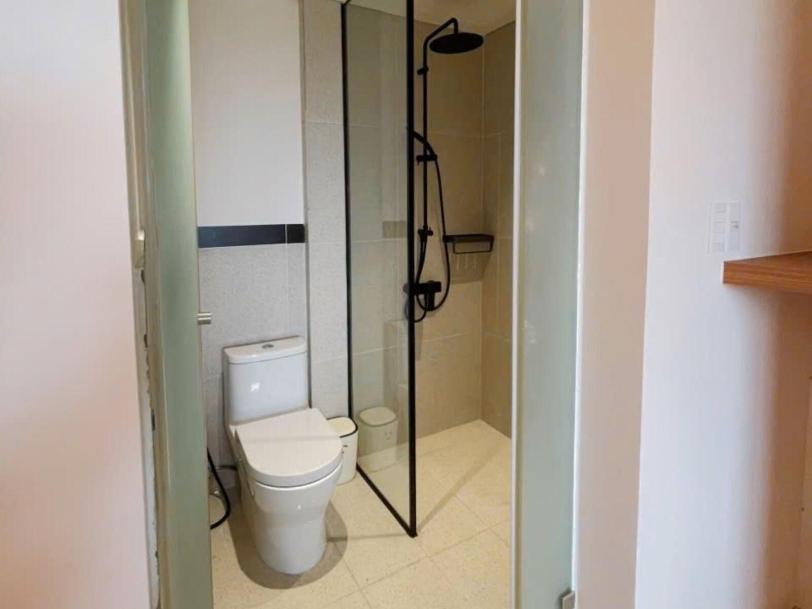 A bathroom with a toilet, a shower enclosure, and a tiled floor.