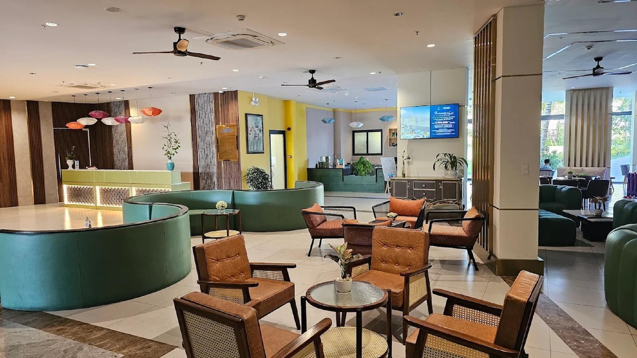 A hotel lobby with a reception desk, seating area, and a television screen.